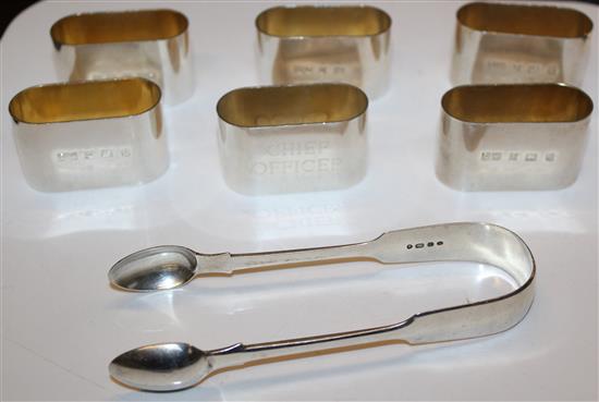 Six silver napkin rings and a pair of tongs